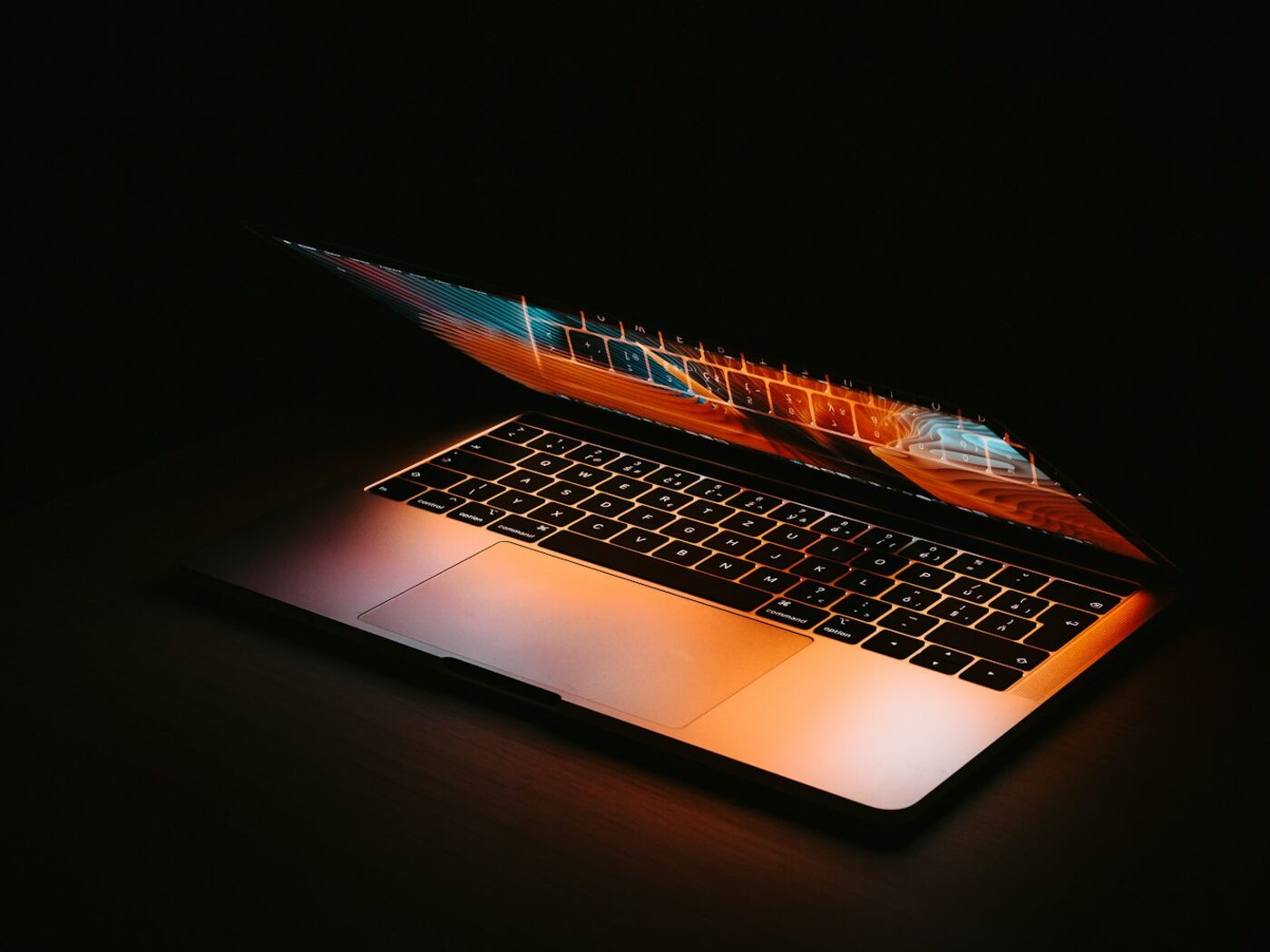 Aufgeklapptes MacBook leuchtet warm im Dunkeln, Sinnbild für konzentrierte Webentwicklung